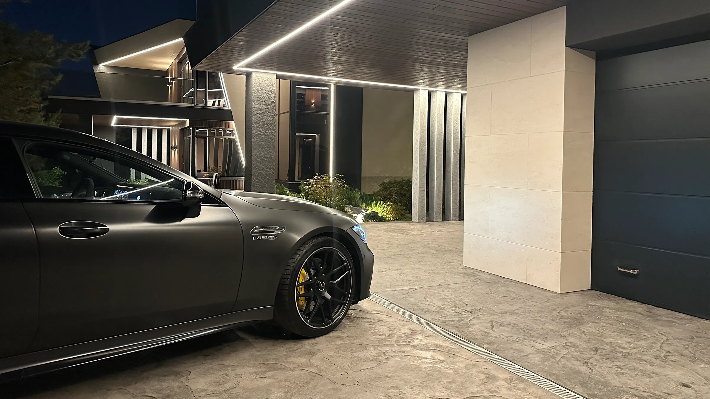 View of the rear and side of a Porsche 911 Turbo S in Oak Green Metallic Neo, standing in a courtyard.