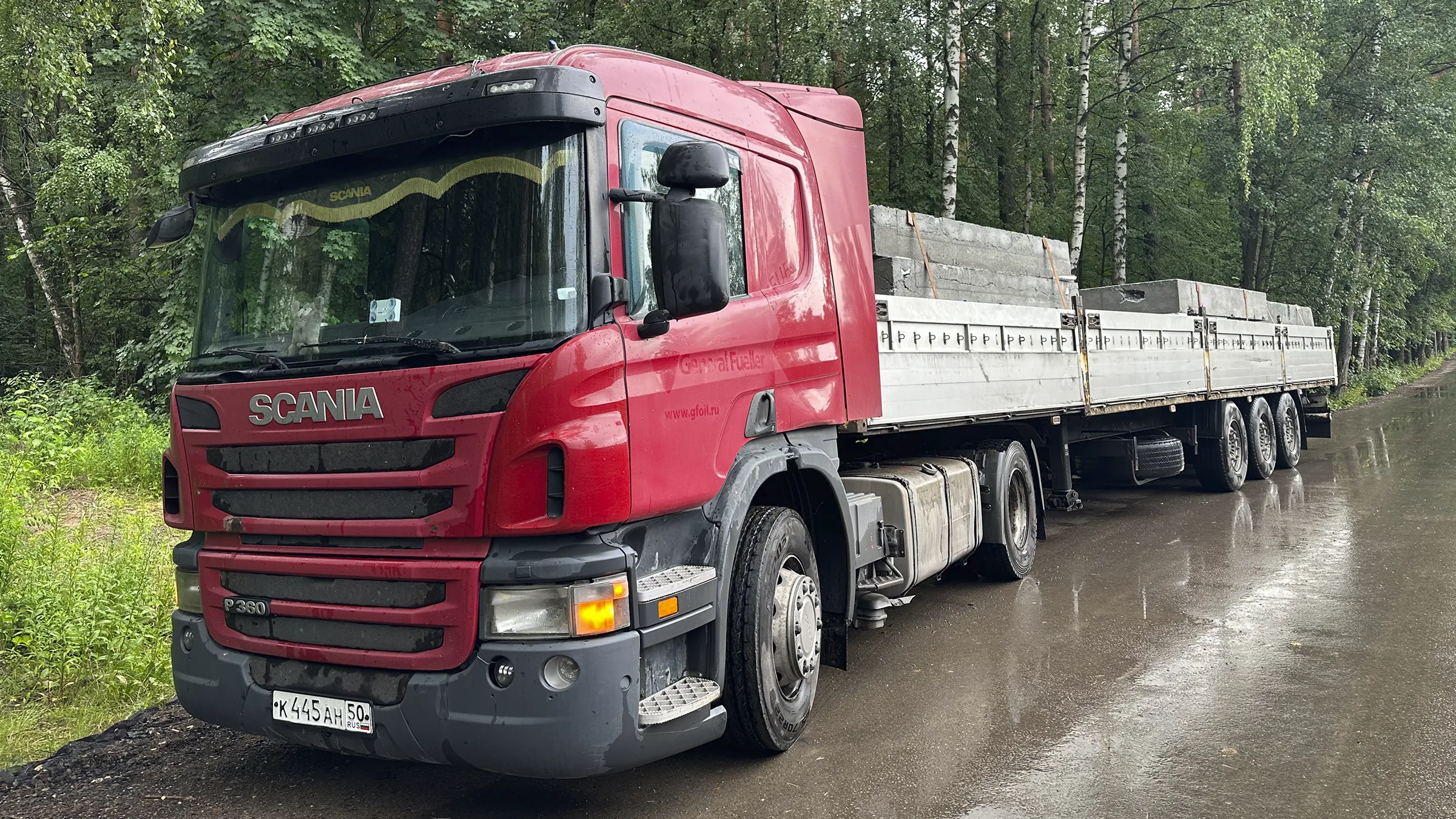 View of the rear and side of a Porsche 911 Turbo S in Oak Green Metallic Neo, standing in a courtyard.